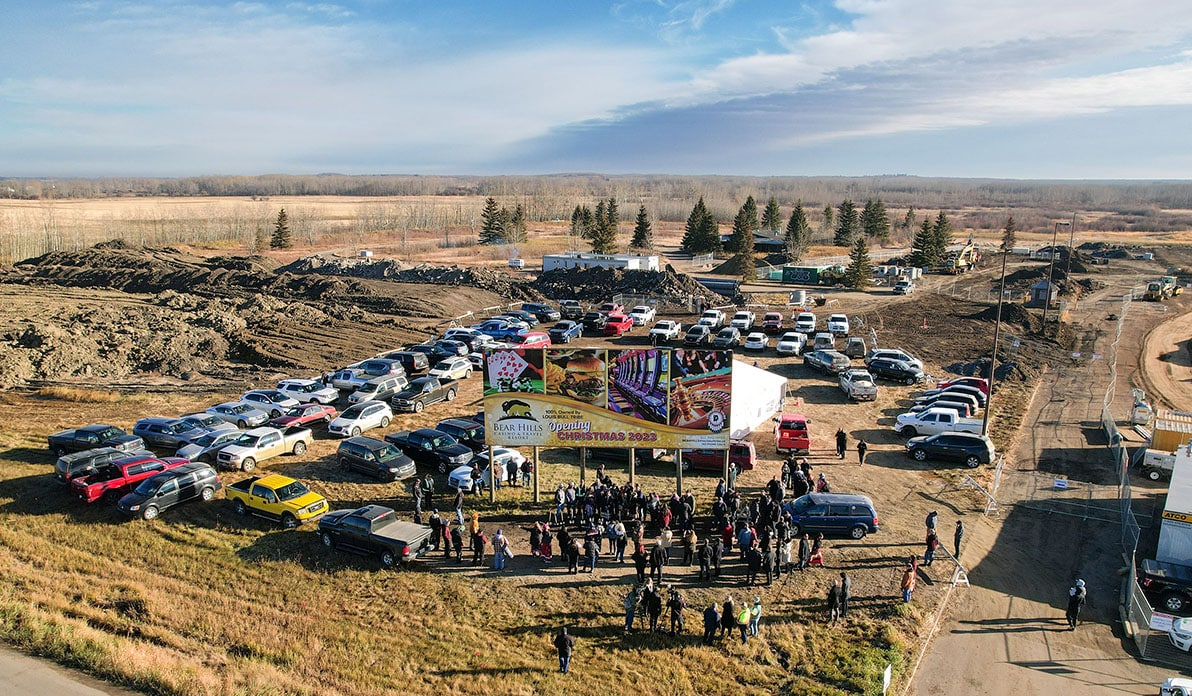 An aerial view of a large group of people gathered outside, around a billboard for the Bear Hills Casino