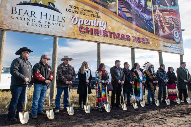12 people standing outside in a row holding golden shovels for a groundbreaking event
