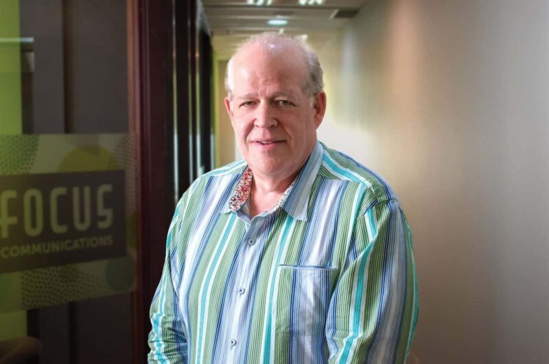 Man in blue striped shirt looking into the camera.